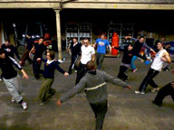 DR. BEAT Bboying / Breakdancing with young people in Wester Hailes on brick paving beside lit street light, fence and house at night